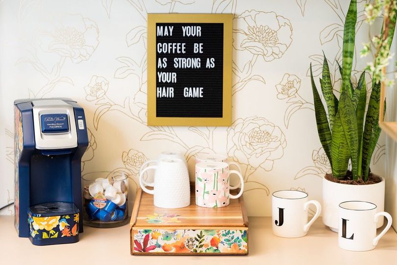 Coffee station with a sign that says "May your coffee be as strong as your hair game"